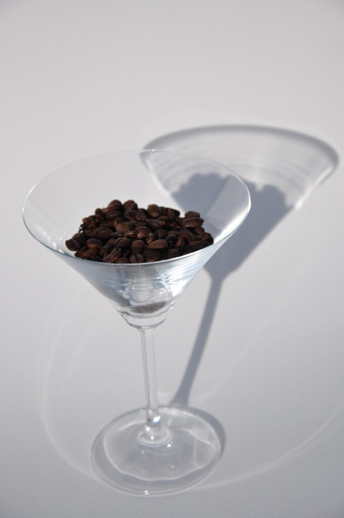 Clear stemmed glass filled with roasted coffee beans.