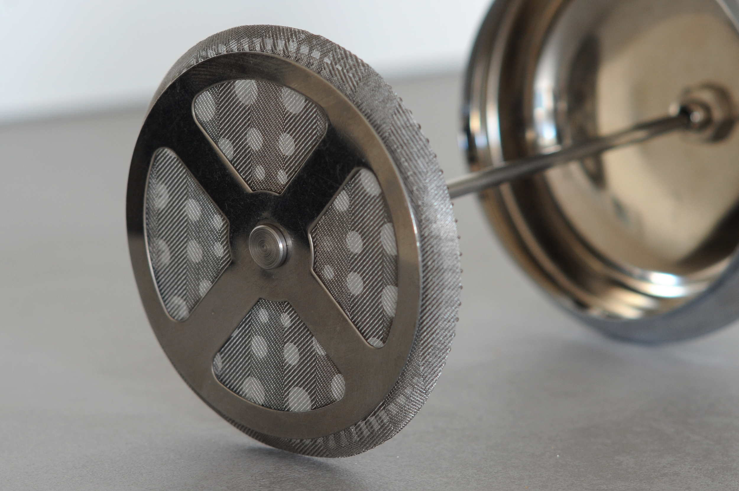 Close-up of the underside of a circular metal French press mesh filter.