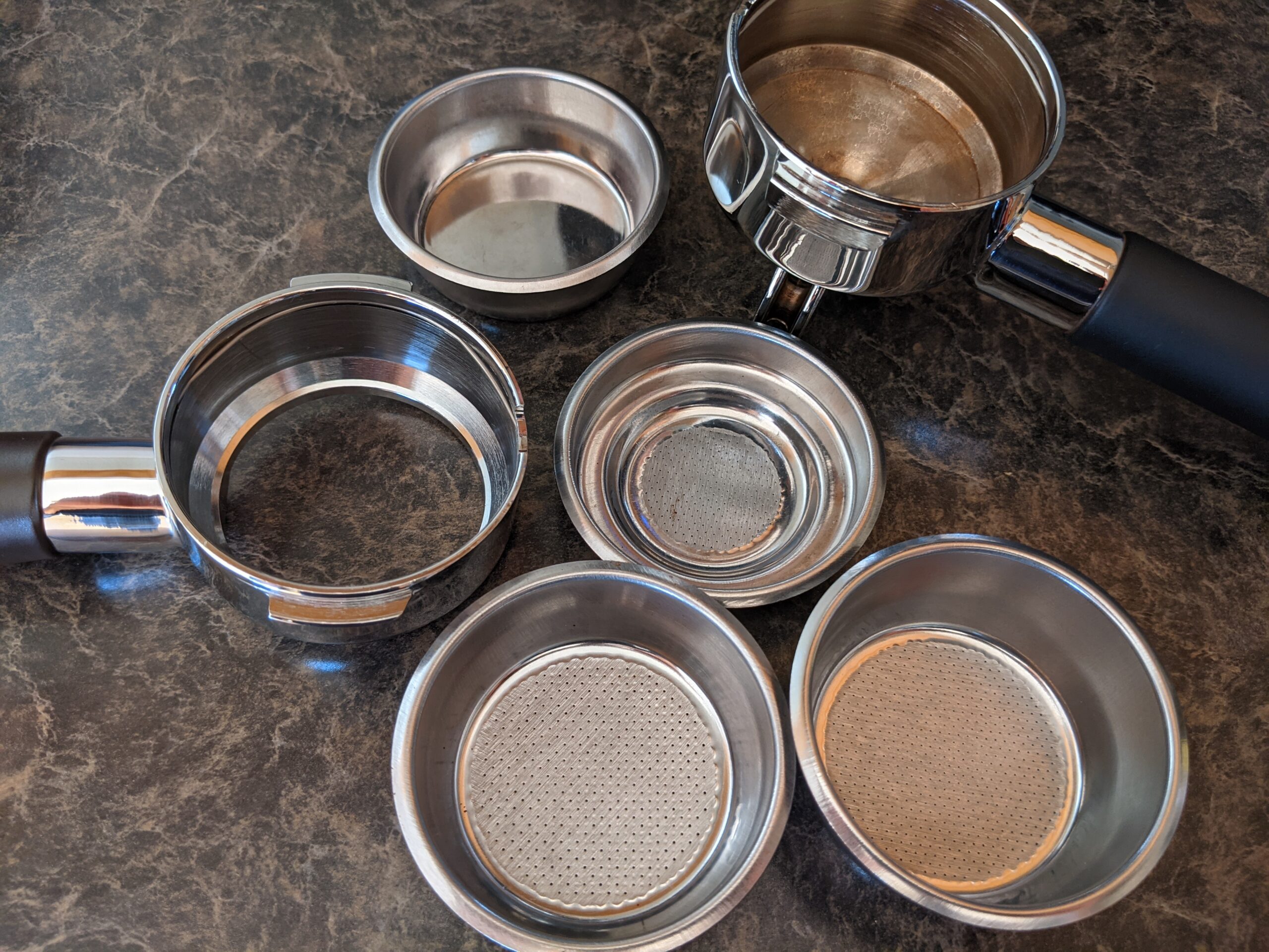 Assorted espresso portafilters and removable filter baskets.